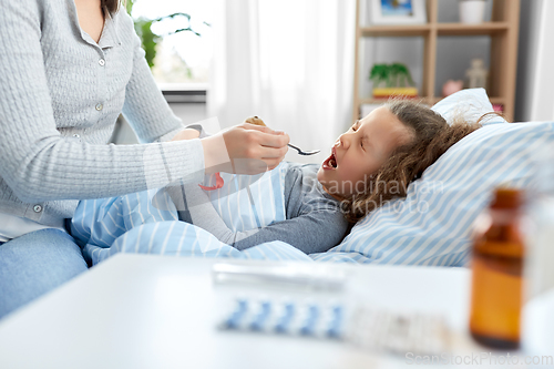 Image of mother giving cough syrup to sick daughter