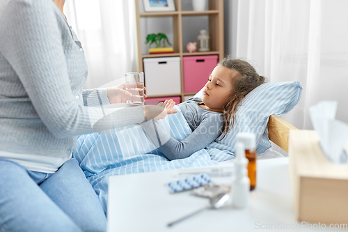 Image of mother giving medicine to sick little daughter