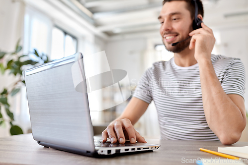 Image of man with headset and laptop working at home