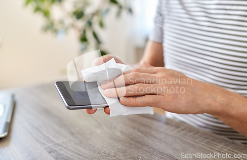 Image of man cleaning phone with wet wipe at home office