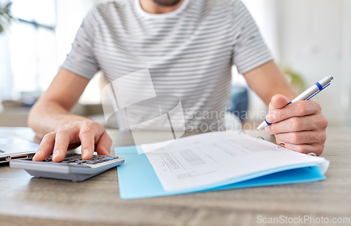 Image of man with files and calculator works at home office