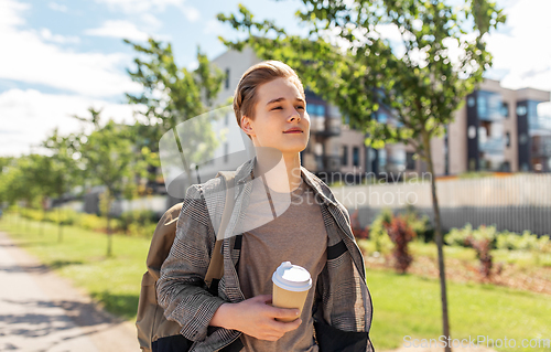 Image of young man with backpack drinking coffee in city