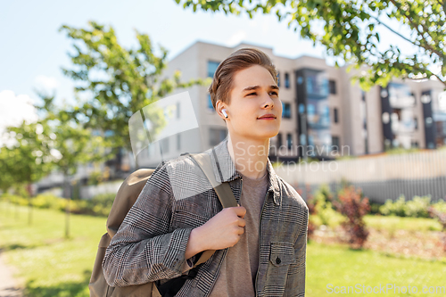 Image of young man with earphones and backpack in city