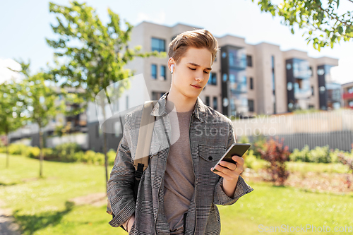 Image of teenage boy with earphones and smartphone in city