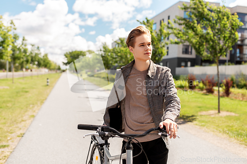 Image of young man with bicycle walking along city street