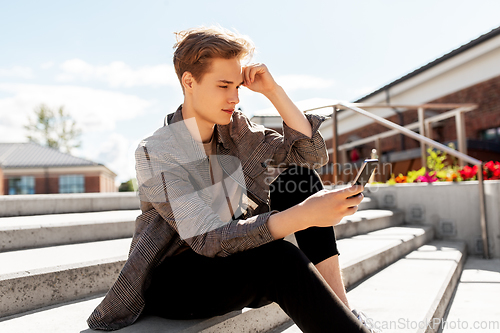 Image of teenage boy using smartphone in city