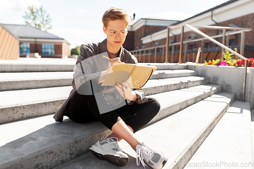 Image of young man with notebook or sketchbook in city