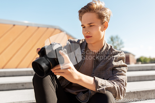 Image of young man with camera photographing in city