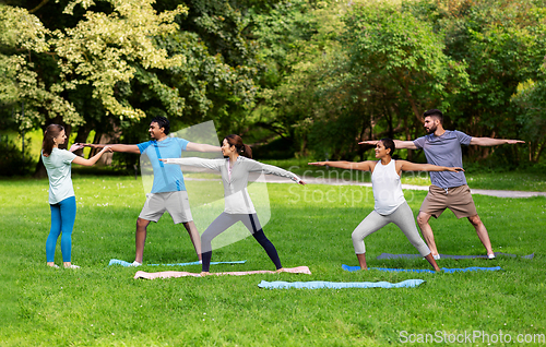 Image of group of people doing yoga at summer park
