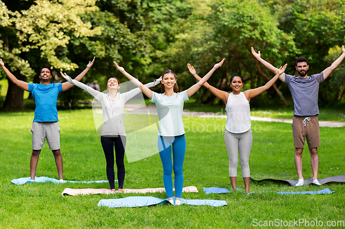 Image of group of people doing yoga at summer park