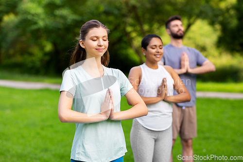 Image of group of people doing yoga at summer park