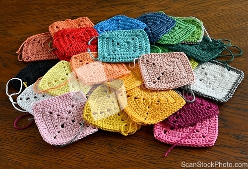 Image of colorful knitted squares on the wooden background