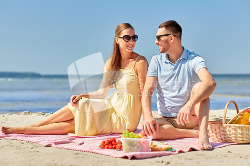 Image of happy couple having picnic on summer beach