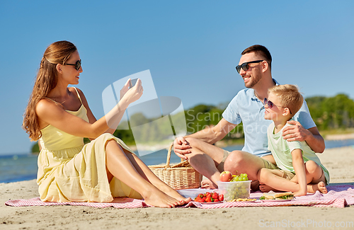 Image of family with smartphone photographing on beach