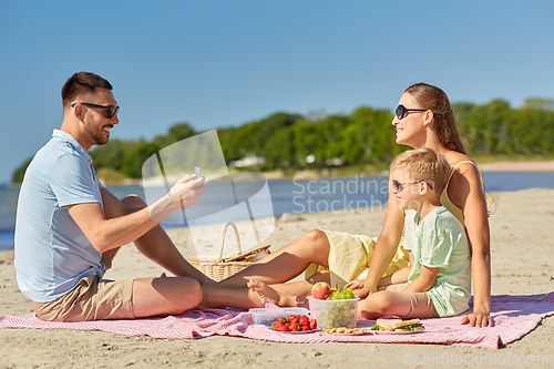 Image of family with smartphone photographing on beach