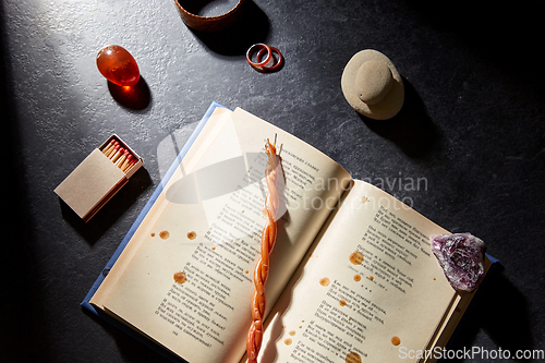 Image of magic book, wax candle, matches and gem stones