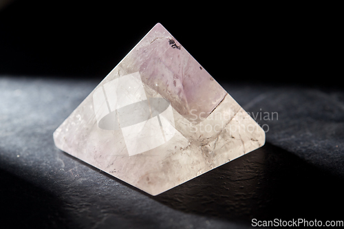 Image of quartz crystal pyramid on slate stone in darkness