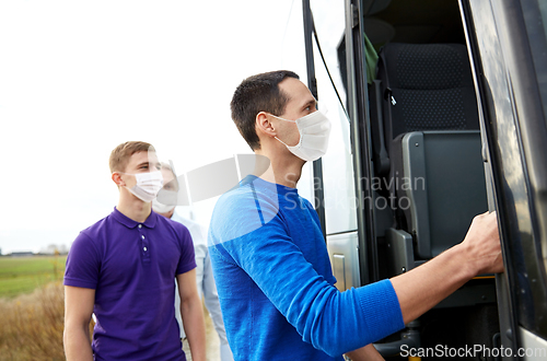 Image of group of passengers in masks boarding travel bus