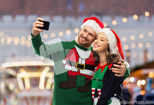 Image of happy couple in christmas sweaters taking selfie