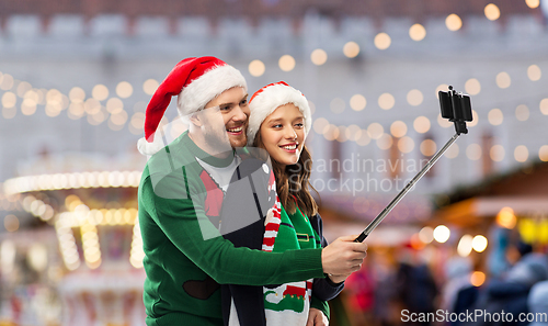 Image of happy couple in christmas sweaters taking selfie