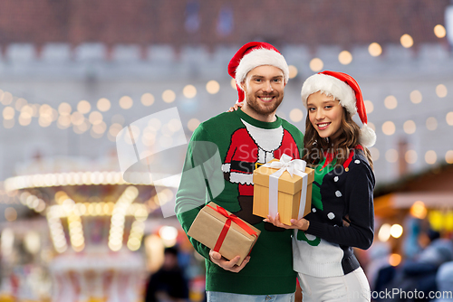 Image of happy couple in christmas sweaters with gifts