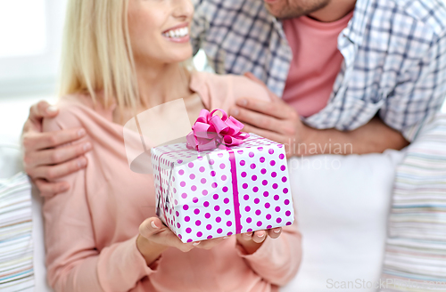 Image of happy couple with gift box at home