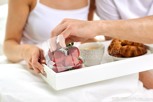 Image of couple having breakfast in bed at home