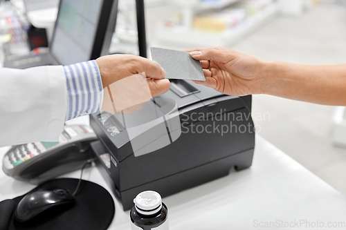 Image of close up of hand giving bank card to pharmacist