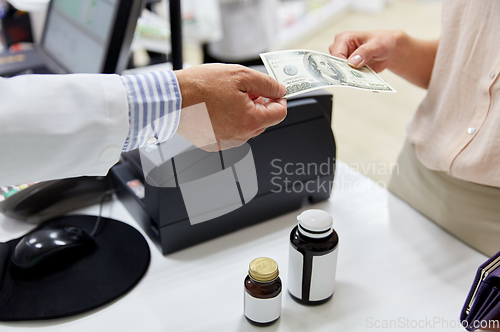 Image of pharmacist taking money from customer at pharmacy