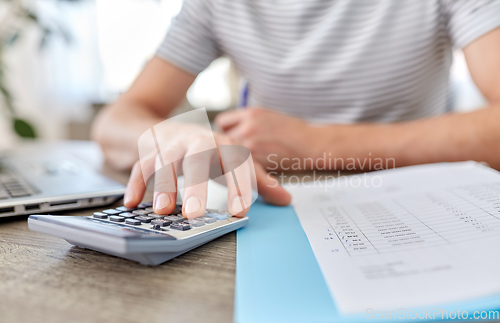 Image of man with files and calculator works at home office