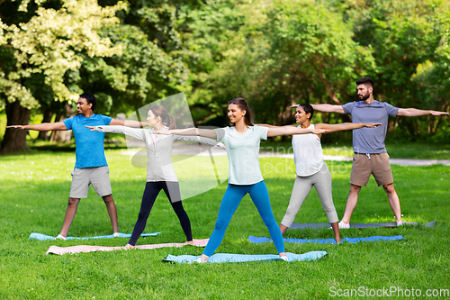 Image of group of people doing yoga at summer park