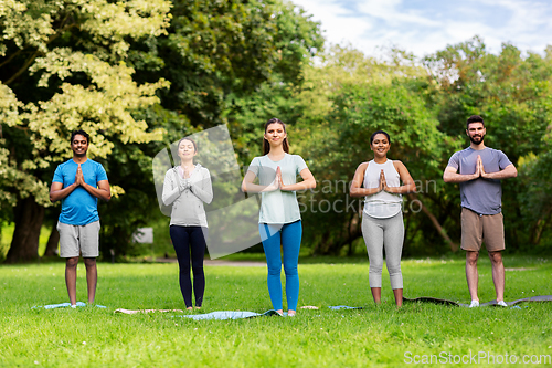 Image of group of people doing yoga at summer park