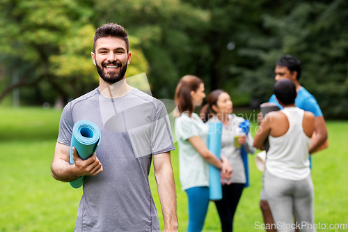 Image of smiling man with yoga mat over group of people