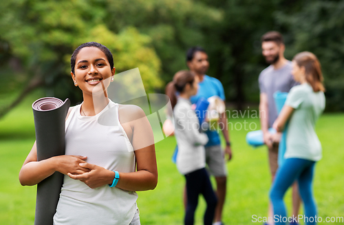 Image of smiling woman with yoga mat over group of people