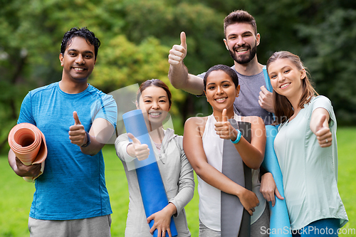 Image of people with yoga mats showing thumbs up at park