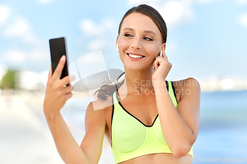 Image of woman with earphones and smartphone doing sports