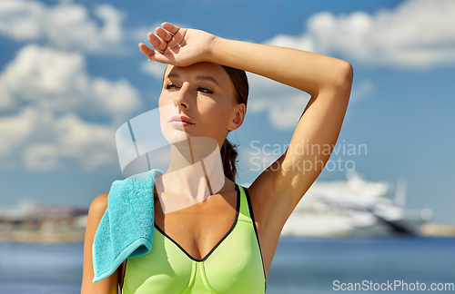 Image of tired woman with towel after sports outdoors