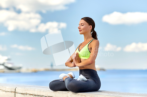 Image of young woman meditating in lotus pose at seaside