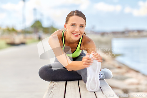 Image of happy young woman doing sports and stretching leg