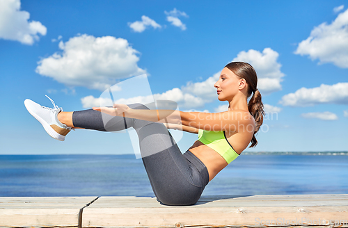Image of young woman exercising on sea promenade