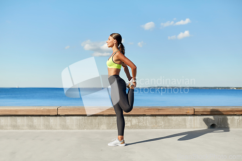 Image of happy young woman doing sports and stretching leg