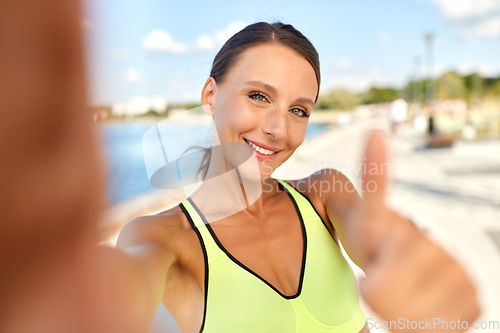 Image of sporty woman taking selfie and showing thumbs up