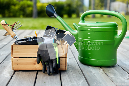 Image of box with garden tools and watering can in summer