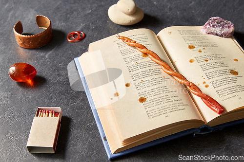 Image of magic book, wax candle, matches and gem stones
