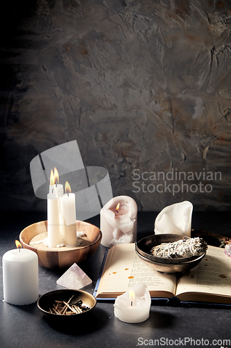 Image of magic book, sage, burning candles and ritual staff