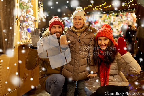 Image of happy family waving hands at christmas market