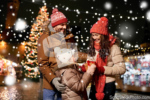 Image of happy family with gift at christmas market in city