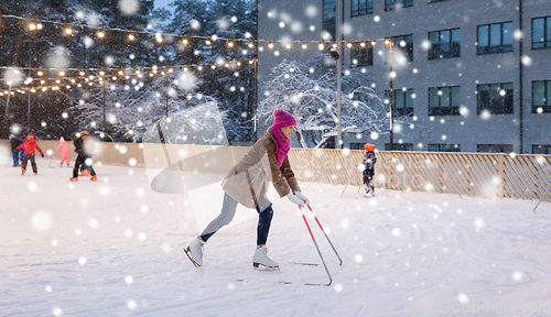 Image of happy woman at outdoor skating rink in winter