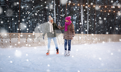 Image of happy couple holding hands on skating rink