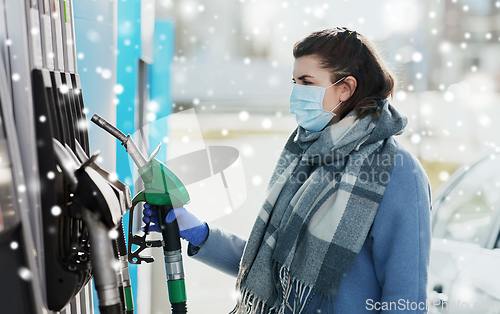 Image of young woman wearing medical mask at gas station